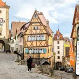 Romantische Gassen und Fachwerkhäuser in Rothenburg ob der Tauber. Ein Smartphone zeigt eine Stadtführung an.