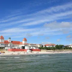 Prachtvolles Gebäude am Strand des Ostseebad Binz, mit roten Dächern und Türmen, unter blauem Himmel mit Wolken.