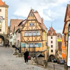 Romantische Gassen und Fachwerkhäuser in Rothenburg ob der Tauber. Ein Smartphone zeigt eine Stadtführung an.