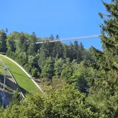 Der Skywalk Willingen überspannt den Wald und bietet einen atemberaubenden Blick auf die Sprungschanze und die grüne Landschaft.