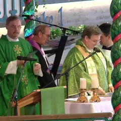 Priester in grünen Gewändern bei einem Gottesdienst in den Kirchen. Kerzen und ein Kreuz stehen auf dem Altar.