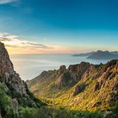 Sonnenuntergang über felsigen Bergen und dem Meer. Ein perfekter Ort für coole Reiseziele, der zum Erkunden einlädt.