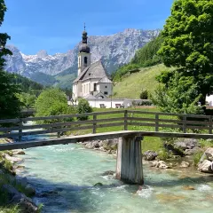 Idyllische Kirche mit Bergkulisse und Fluss – ein malerisches Motiv, das zu den beliebten Reisezielen Deutschlands zählt.