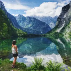 Frau genießt die Aussicht auf einen Bergsee in Bayern. Hier kann man wandern und die Natur erleben.