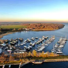 Boote im **Putbus Hafen** liegen friedlich im Wasser, umgeben von modernen Häusern auf Stelzen und einer malerischen Landschaft.