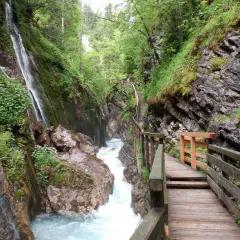 Holzstege führen durch die Klamm Berchtesgaden, vorbei an tosendem Wasser und moosbewachsenen Felsen.