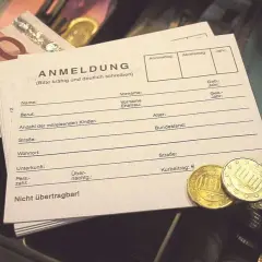 Anmeldeformular mit Euro-Scheinen und Münzen. Hier wird der Kurbeitrag für die Kurtaxe bei Schwerbehinderung eingetragen.