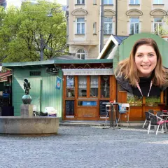 Lächelnde Frau vor einem Stehcafé in Haidhausen. Ein Brunnen und ein kleiner Junge als Statue sind im Vordergrund.