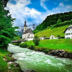 Grüner Fluss fließt an Kirche und Haus vorbei. Hier kann man in Berchtesgaden die Natur genießen und die Seele baumeln lassen.