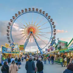Buntes Treiben auf dem Frühlingsfest München mit Riesenrad, Essensständen und vielen Besuchern.