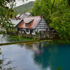 Ein Fachwerkhaus am kristallklaren Wasser, umgeben von üppigem Grün. Ein idyllischer Ort, einer der vielen Geheimtipps Deutschland Natur.