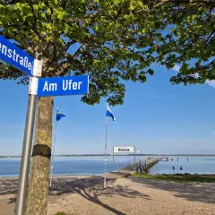 Schilder "Hafenstraße" und "Am Ufer" weisen den Weg zur **dranske strandpromenade**. Ein Steg führt ins ruhige Wasser.