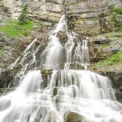 Ein beeindruckender, mehrstufiger murnau wasserfall stürzt über moosbewachsene Felsen in die Tiefe, umgeben von steilen, grünen Hängen.