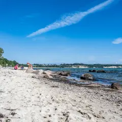 Kinder spielen am lobbe strand. Sand, Steine und das Meer prägen die Szenerie unter blauem Himmel.