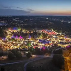 Nachtansicht des beleuchteten Tollwood Festivals im Olympiapark München mit bunten Zelten und Lichtern.