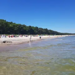 Sonniger Tag am Thiessow Strand mit vielen Strandkörben, Menschen und einem ruhigen Meer.