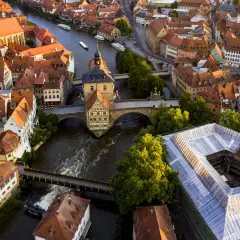 Luftaufnahme von Bamberg: Das Alte Rathaus thront über dem Fluss, umgeben von roten Dächern. Ein perfekter Ort für einen Bamberg Tagesausflug.
