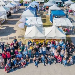 Große Gruppe feiert auf dem wochenmarkt thiessow. Viele Stände mit Waren und Zelten im Hintergrund.