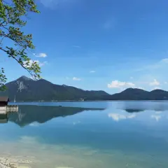Karibik-Feeling am Walchensee: Ein Boot gleitet über das spiegelglatte Wasser, Berge im Hintergrund laden zum Baden ein.