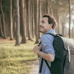 Ein Mann mit Rucksack wandert durch den gespensterwald nienhagen, die Bäume ragen mystisch in den Himmel.