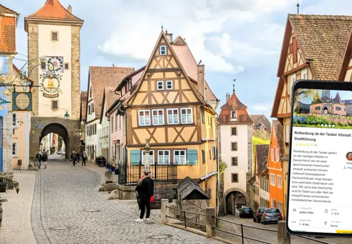 Romantische Gassen und Fachwerkhäuser in Rothenburg ob der Tauber. Ein Smartphone zeigt eine Stadtführung an.