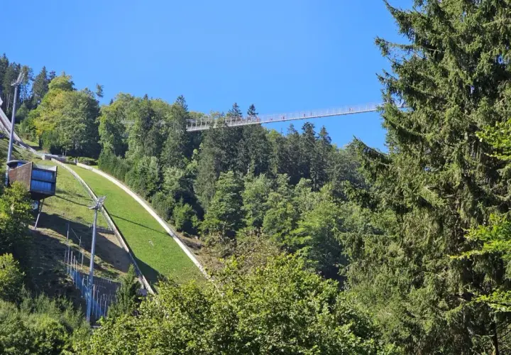 Der Skywalk Willingen überspannt den Wald und bietet einen atemberaubenden Blick auf die Sprungschanze und die grüne Landschaft.