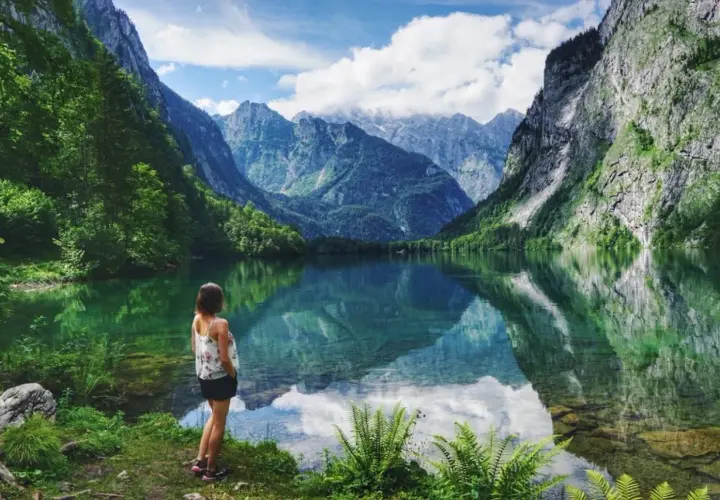 Frau genießt die Aussicht auf einen Bergsee in Bayern. Hier kann man wandern und die Natur erleben.