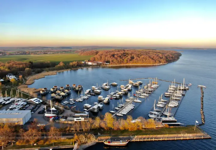 Boote im **Putbus Hafen** liegen friedlich im Wasser, umgeben von modernen Häusern auf Stelzen und einer malerischen Landschaft.
