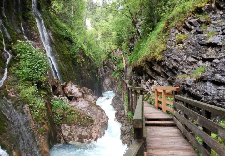 Holzstege führen durch die Klamm Berchtesgaden, vorbei an tosendem Wasser und moosbewachsenen Felsen.