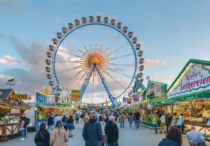 Buntes Treiben auf dem Frühlingsfest München mit Riesenrad, Essensständen und vielen Besuchern.