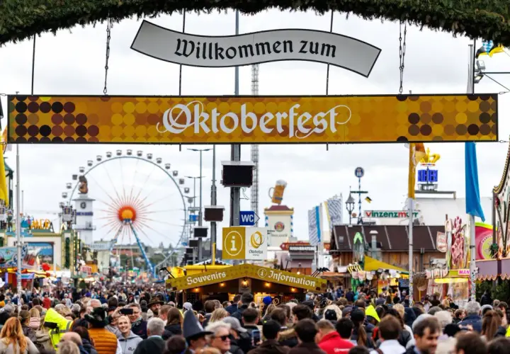 Volle Gassen beim Oktoberfest. Ein Schild verkündet "Willkommen zum Oktoberfest". Eintritt kostet das Oktoberfest nicht, aber die Attraktionen und das Bier.