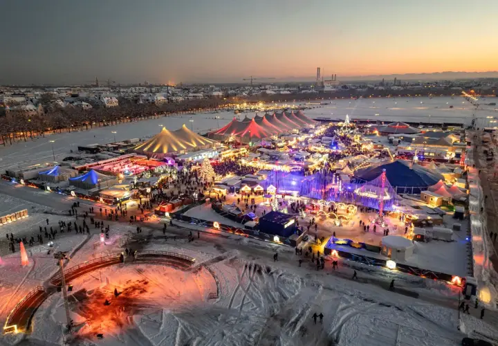 Winterzauber auf dem weihnachtsmarkt theresienwiese. Bunte Lichter, Schnee und Menschenmassen unter Zelten und Lichtern.