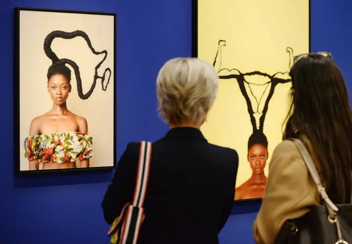 Besucher betrachten Kunstwerke bei der ausstellung hypo kunsthalle. Ein Bild zeigt eine Frau mit afrikanisch geformten Haaren, das andere eine Frau mit Gebärmutter-Frisur.
