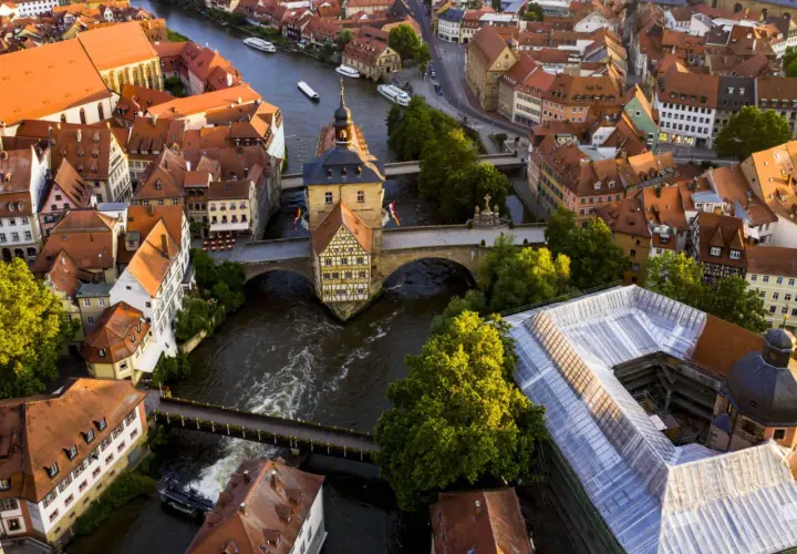 Luftaufnahme von Bamberg: Das Alte Rathaus thront über dem Fluss, umgeben von roten Dächern. Ein perfekter Ort für einen Bamberg Tagesausflug.