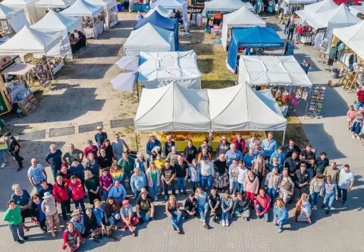 Große Gruppe feiert auf dem wochenmarkt thiessow. Viele Stände mit Waren und Zelten im Hintergrund.