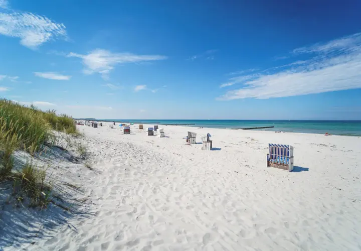 Ein perfekter Hiddensee Urlaub: Weißer Sandstrand, blaue Ostsee und Strandkörbe laden zum Entspannen ein.