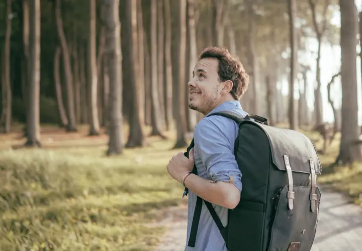 Ein Mann mit Rucksack wandert durch den gespensterwald nienhagen, die Bäume ragen mystisch in den Himmel.