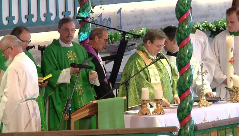 Priester in grünen Gewändern bei einem Gottesdienst in den Kirchen. Kerzen und ein Kreuz stehen auf dem Altar.