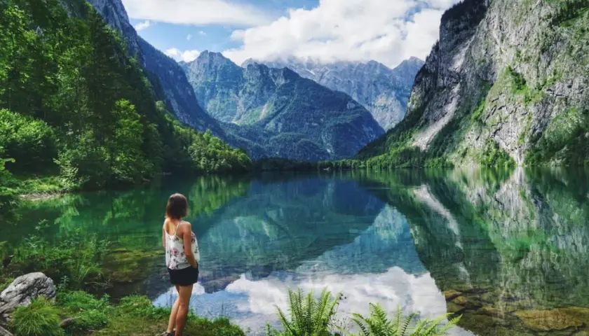 Frau genießt die Aussicht auf einen Bergsee in Bayern. Hier kann man wandern und die Natur erleben.