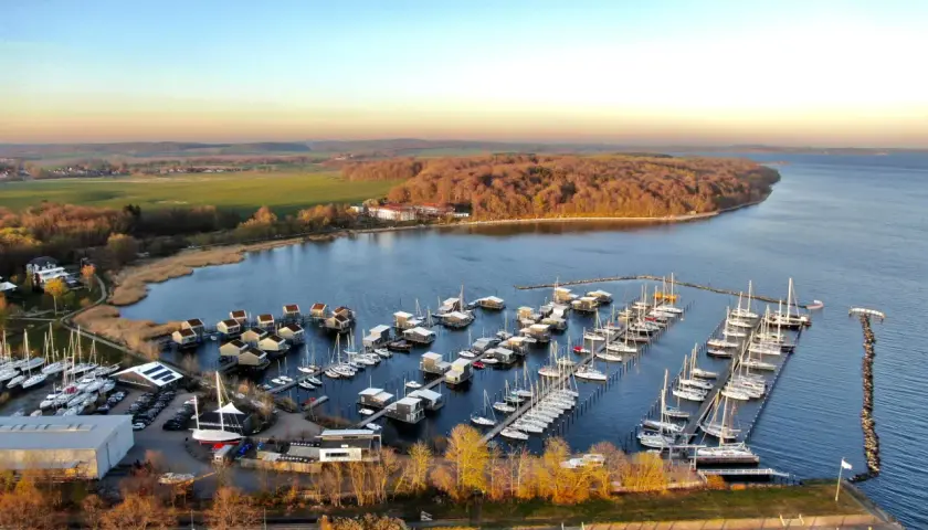 Boote im **Putbus Hafen** liegen friedlich im Wasser, umgeben von modernen Häusern auf Stelzen und einer malerischen Landschaft.