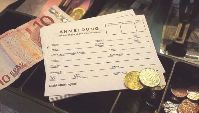 Anmeldeformular mit Euro-Scheinen und Münzen. Hier wird der Kurbeitrag für die Kurtaxe bei Schwerbehinderung eingetragen.