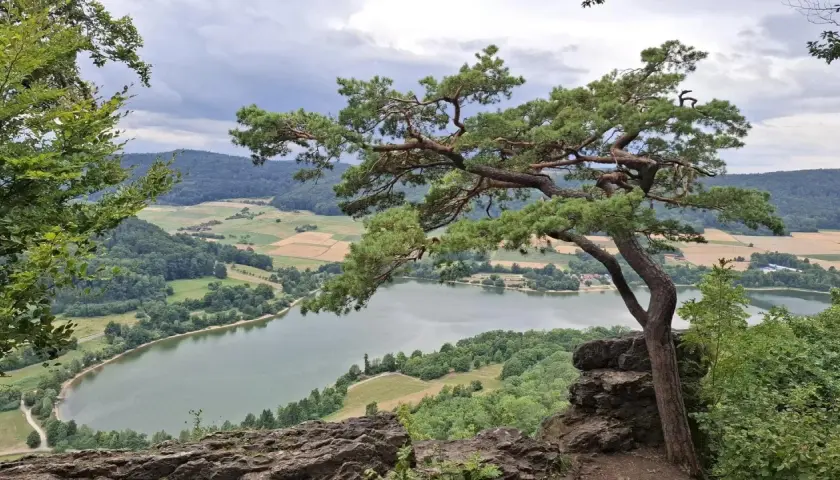Blick vom Felsen auf den Happurger Stausee. Ein Baum ragt ins Bild, ideal für eine Wanderung.