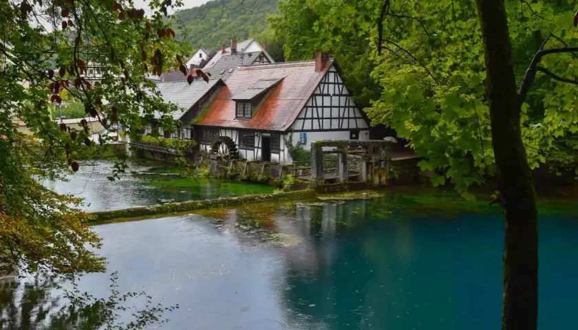 Ein Fachwerkhaus am kristallklaren Wasser, umgeben von üppigem Grün. Ein idyllischer Ort, einer der vielen Geheimtipps Deutschland Natur.