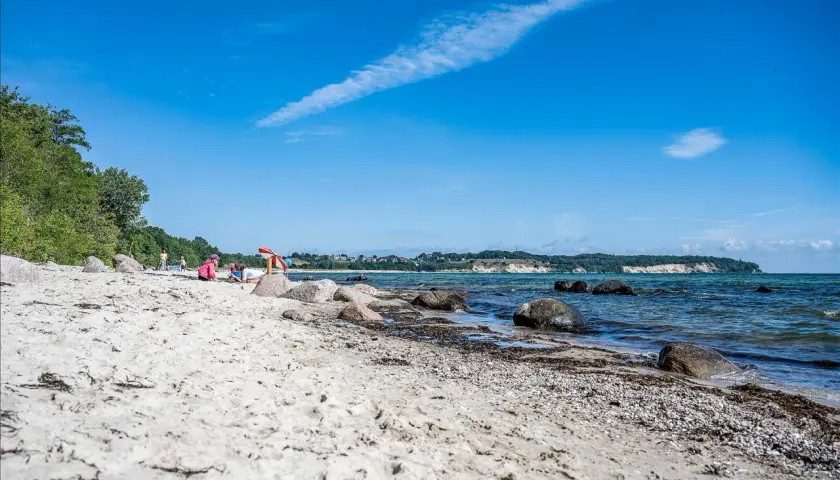 Kinder spielen am lobbe strand. Sand, Steine und das Meer prägen die Szenerie unter blauem Himmel.