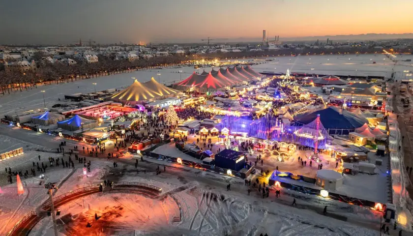 Winterzauber auf dem weihnachtsmarkt theresienwiese. Bunte Lichter, Schnee und Menschenmassen unter Zelten und Lichtern.