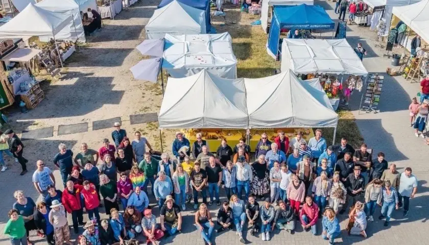Große Gruppe feiert auf dem wochenmarkt thiessow. Viele Stände mit Waren und Zelten im Hintergrund.