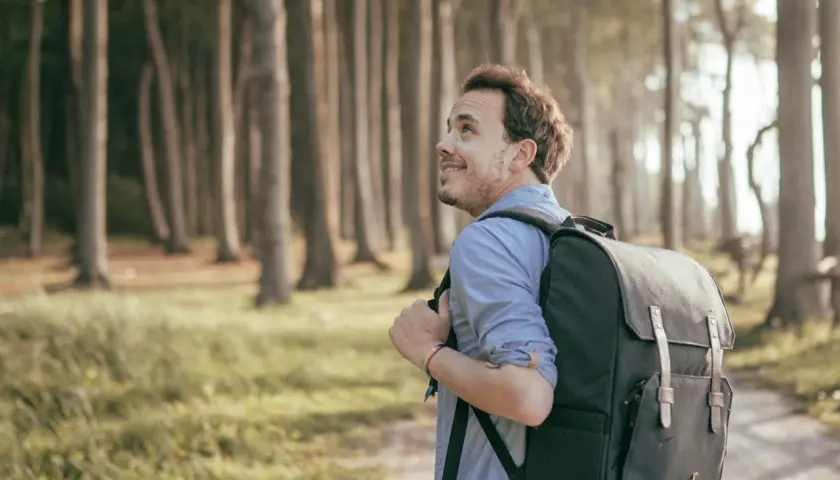 Ein Mann mit Rucksack wandert durch den gespensterwald nienhagen, die Bäume ragen mystisch in den Himmel.