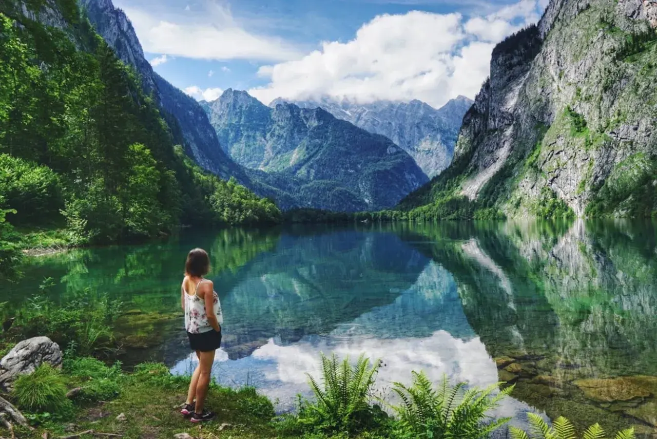 Frau genießt die Aussicht auf einen Bergsee in Bayern. Hier kann man wandern und die Natur erleben.