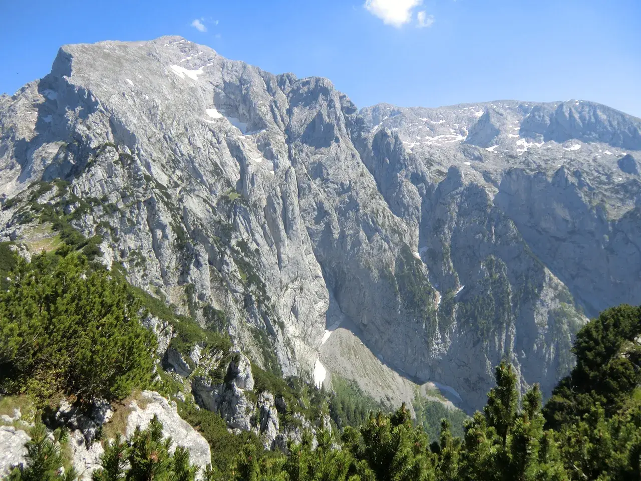 Majestätische Bergkulisse mit felsigen Hängen und grünen Nadelbäumen, ideal für eine Kehlsteinhaus Wanderung.