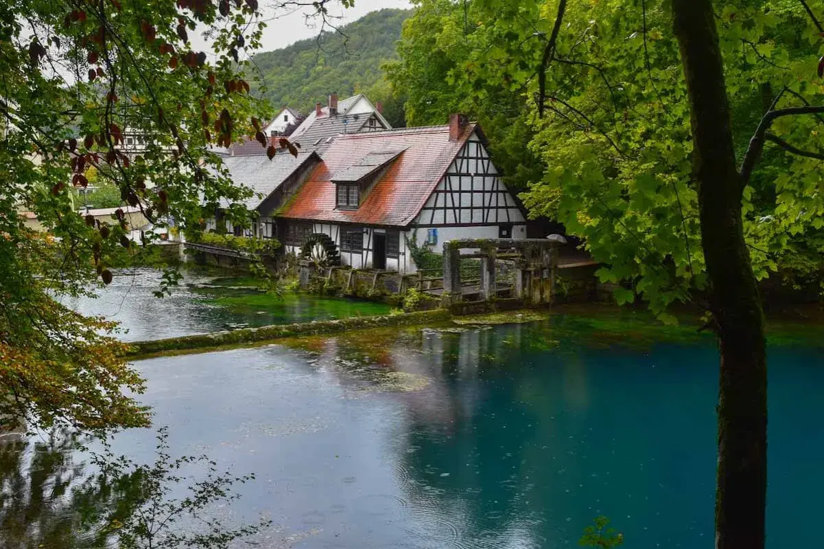 Ein Fachwerkhaus am kristallklaren Wasser, umgeben von üppigem Grün. Ein idyllischer Ort, einer der vielen Geheimtipps Deutschland Natur.
